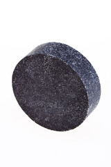 Black round piece of soap on a white background. 