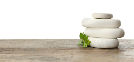 Stack of spa stones and green branch on wooden table against white background. Space for text