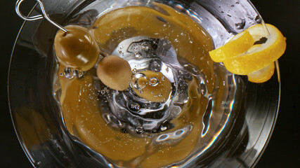 Splashing olives into a martini glass, top down shot.