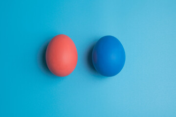 Pink and blue eggs. Eggs on a blue background. Two colored chicken eggs.