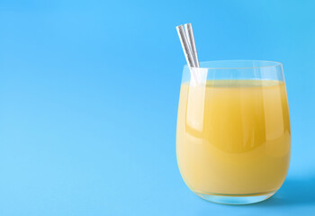 Glass of delicious juice on light blue background, space for text