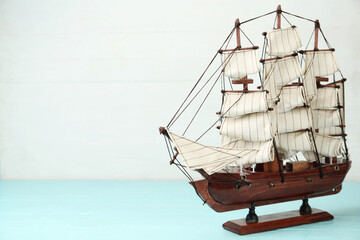 Beautiful ship model on light blue wooden table. Space for text