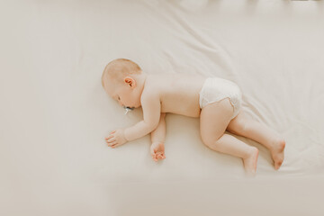 Sleeping little baby in a diaper sleeps in a crib