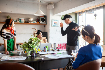 同僚に企画のプレゼンをするシニアデザイナー