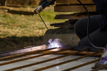 welding of a metal framework, works take place on the street, the process of welding of metal is visible in a close-up.