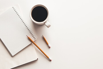 Office desk table with supplies, coffee cup and flower. Top view
