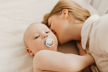 Happy mother smiling at her baby lying on the bed