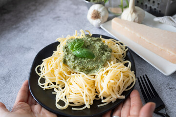 
Delicious pasta dish held by hands with homemade pesto sauce made with basil, parmesan, garlic, extra virgin olive oil and nuts