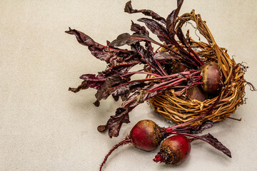 Fresh homegrown beetroot with leaves in wicker basket on light stone concrete background