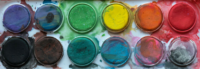 Close up view of messy colorful watercolor palette.