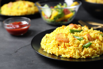 Delicious rice pilaf with meat served on dark table, closeup. Space for text