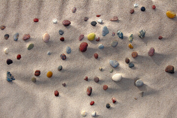 Still life image about colorful round pebbles, marbles on beach sand for backgrounds, wallpapers.
