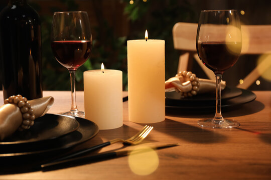 Table setting with textured wine glasses, candles and leaves. Stock Photo  by puhimec