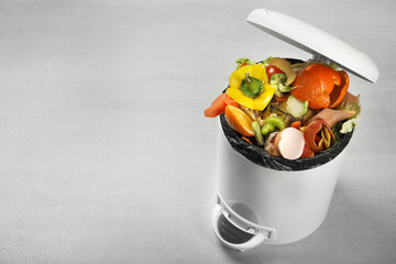 Trash bin with natural garbage on light background, space for text. Composting of organic waste