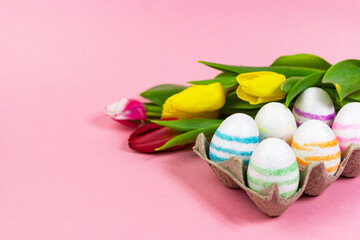 Fototapeta na wymiar Easter painted eggs with tulips on a pink background. Copy space. Easter celebration concept.