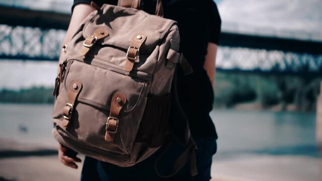 A closeup of a tourist with a backpack and camera walking in a city in HD