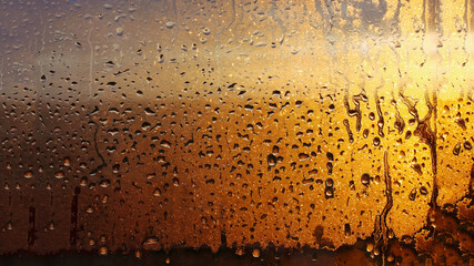 Horizontal natural background with water drops on the window with sunbeams, condensation on the...