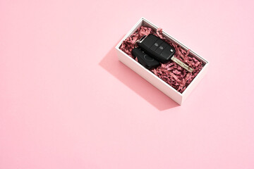 Surprise she will love. Top view of a car key in gift box on pastel pink background