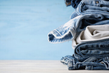 Jeans stacked on a wooden background, place for text. Close-up.