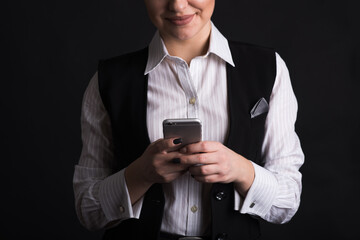 Portrait of a female business woman close-up who uses her smartphone in the studio on a black background