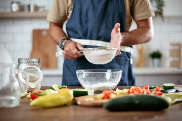 Happy man baking in the kitchen. Man making delicious food at home