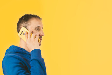 Male talking on his smartphone with a yellow case on a yellow background