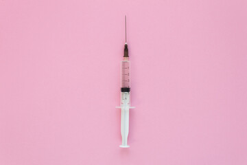 Top view of medical syringe on pink background, health and vaccination concept. Copy space.