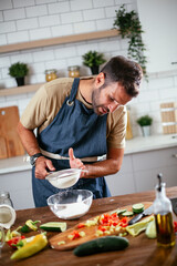 Happy man baking in the kitchen. Man making delicious food at home