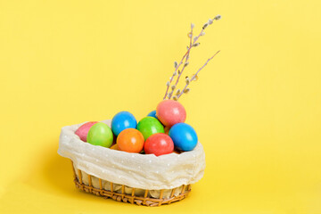 Fototapeta na wymiar painted colorful eggs in a basket for the Easter holiday yellow background
