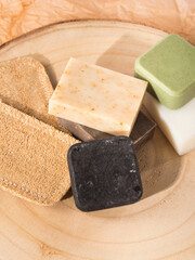 Solid shampoo soap conditioner bar, natural body care eco friendly products and loofah sponges on wooden board and beige neutral paper