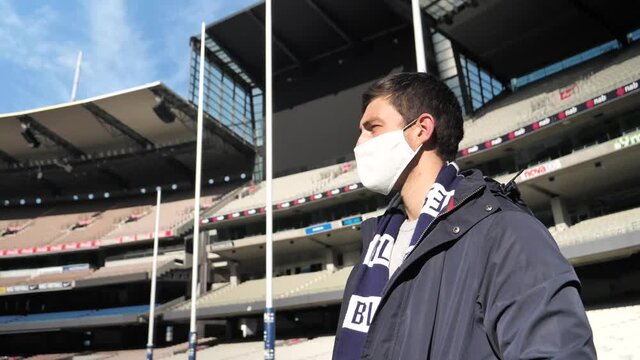 An AFL fan wearing a mask stands in an empty stadium as the coronavirus outbreak stops sport around Australia.