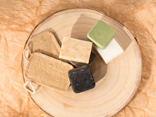 Solid shampoo soap conditioner bar, natural body care eco friendly products and loofah sponges on wooden board and beige neutral paper