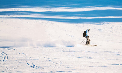 Fototapeta na wymiar Downhill skier riding down a steep alpine slope on a clear sunny day.
