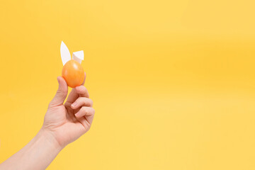 painted colorful eggs in hand with rabbit ears for easter holiday yellow background. background for the poster, place for the text