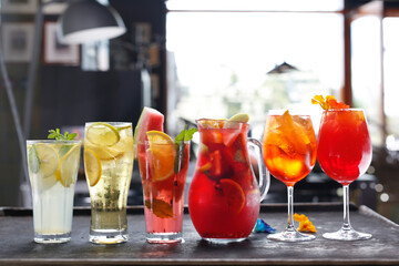 Composition of colorful lemonades, drinks, cocktails in various glasses, on a bar counter, in a restaurant.