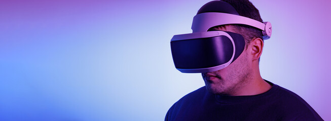 A man in his thirties wearing virtual reality glasses playing video games with a virtual reality headset Fashionable Neon Tinted. Copy space