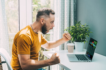 Football fan watching play live broadcast on his laptop computer and cheering for his favourite team