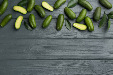 Fresh seedless avocados with green leaves on wooden table, flat lay. Space for text