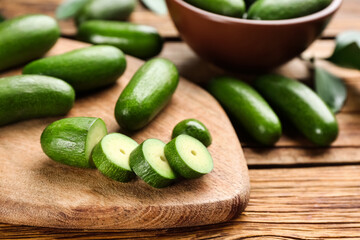 Fresh seedless avocados with green leaves on wooden table, closeup