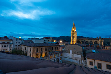 Naklejka premium Old town of the city of Oviedo, in the Principality of Asturias, as seen from a rooftop at dusk. The cathedral of San Salvador can be seen, as well as the Naranco mountain in the background.
