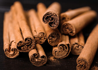 Aromatic cinnamon sticks and spoon with powder on wooden table, closeup