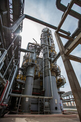 Distillation tower (column) on blue sky with sun background. Oil refinery plant in desert. Wide-angle view