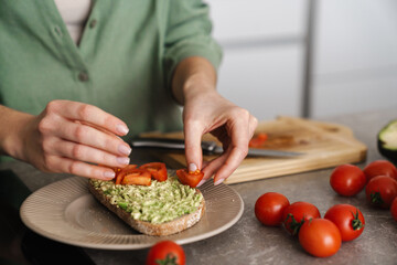 Woman making delicious bruschetta with avocado