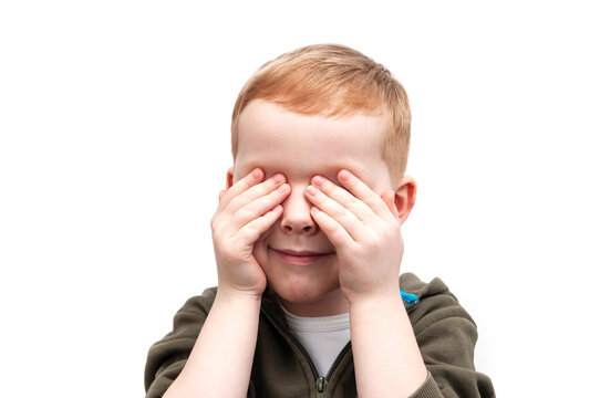 Happy smiling boy with his hands covering the eyes, isolated on white