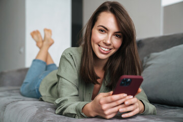 Close up of a smiling attractive woman holding mobile phone