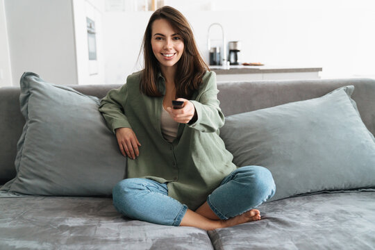 Happy Young Woman Watching Tv On Sofa