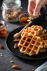 Selective focus shot of a male adding honey on a fresh-baked waffle dessert