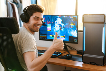 Happy guy in headphones showing thumb up while playing video game © Drobot Dean
