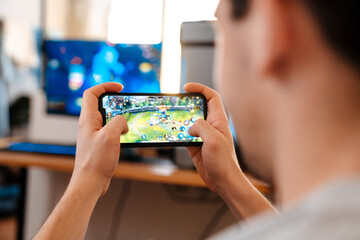 Unshaven brunette guy playing video game on his mobile phone