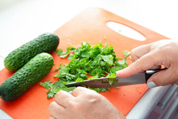 Woman hands cutting parsley on plastic board. Kitchen interier.